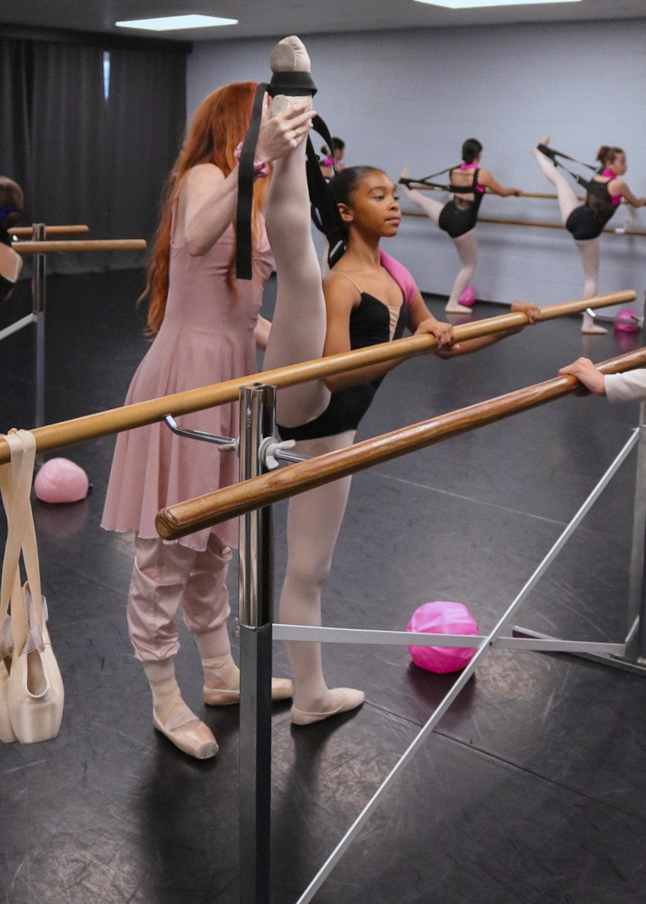 Instructor working with student at the barre